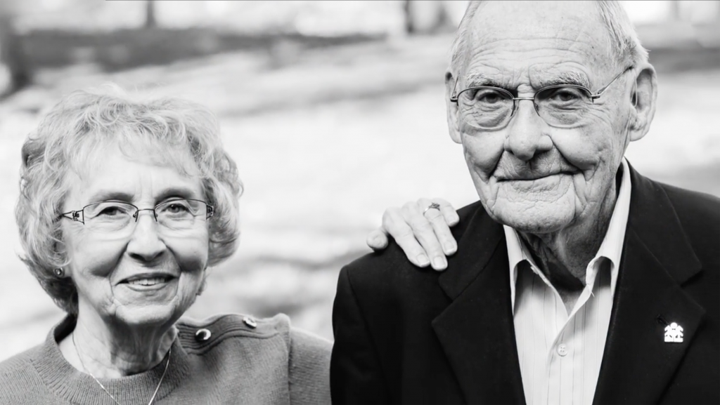 Black and white photograph Glenn and Phyllis Jorgenson in their back yard, her hand on his shoulder.